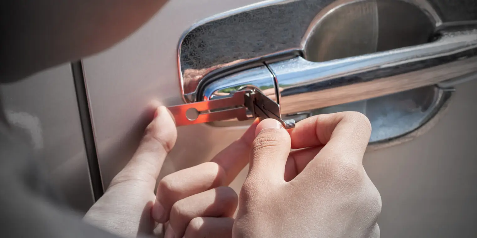 Een slotenmaker past lockpickingtechnieken toe om een auto te ontgrendelen.